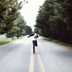 Full length of man running on road against clear sky