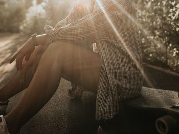 Midsection of woman sitting on skateboard