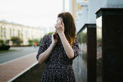 Young woman standing against sky