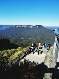 People walking on mountain against clear sky