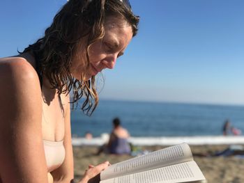 Close-up of woman reading book at beach