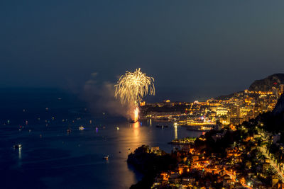 Firework display over sea against sky at night