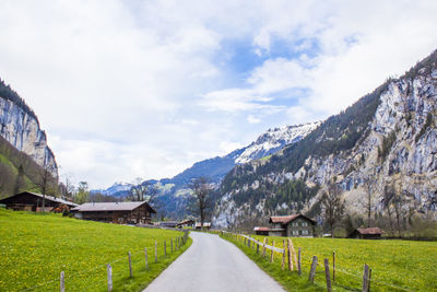 Empty road leading towards mountains against sky