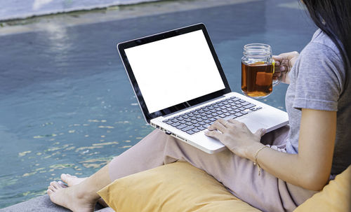 Midsection of woman using laptop at table