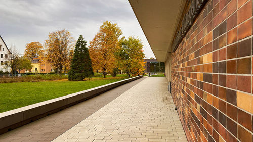 Footpath amidst trees and buildings against sky