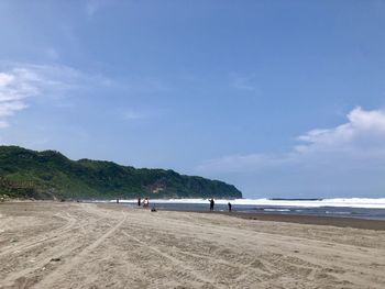 People standing at beach against blue sky