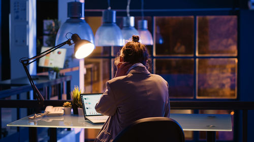 Rear view of man using laptop at home