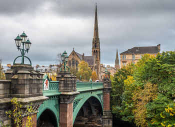 Arch bridge in city against sky