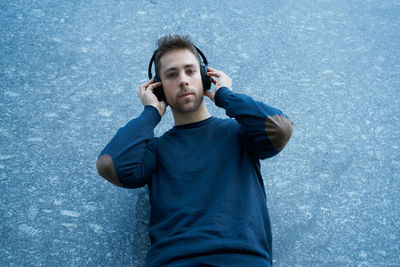 Side view of a modern man in casual clothes leaning against a wall lis