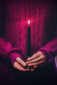 Midsection of girl holding candle in room