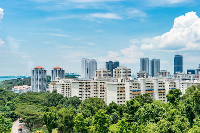 Trees and buildings in city against sky