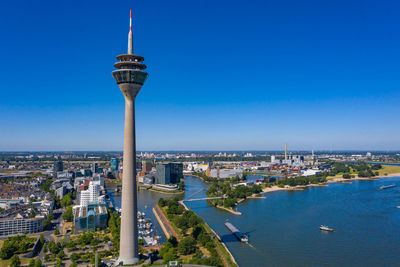 Aerial view of buildings in city against blue sky