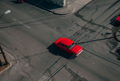 From above of asphalt road intersection with red vintage car among contemporary transports in middle in cuba