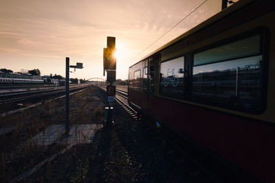 Train at railroad station against sky during sunset