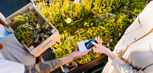 Woman in florist shop is paying with smartphone. money transaction. mobile payment