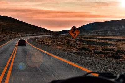 Road seen through car windshield during sunset