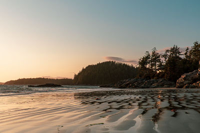 Scenic view of beach against clear sky during sunset