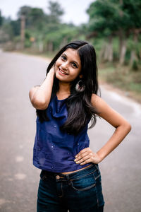 Portrait of smiling young woman standing against wall