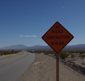 Information sign on road against sky