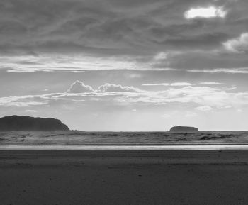 Scenic view of beach against cloudy sky