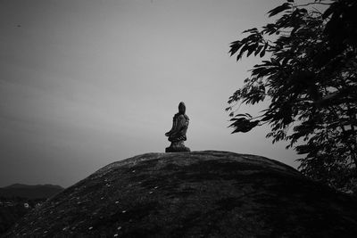 Low angle view of statue on rock against sky