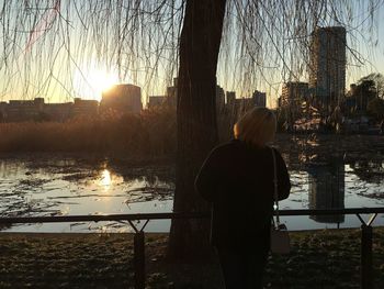 Rear view of woman standing by river in city