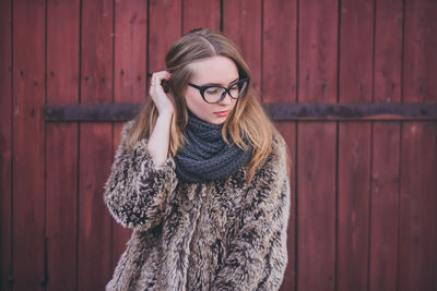 Portrait of young woman standing against brick wall