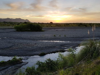 Scenic view of river against sky at sunset