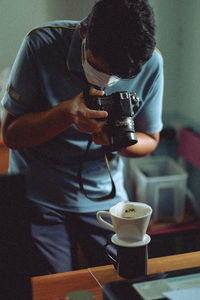 Man photographing drip coffee at cafe