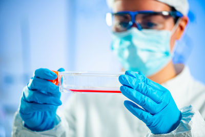 Close-up of scientist holding laboratory glassware while doing experiment in laboratory