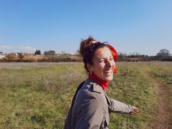 Portrait of young woman standing on field against sky