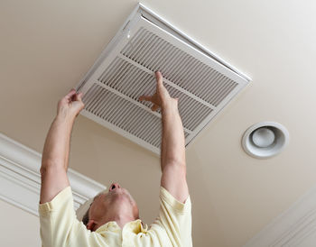 Low angle view of senior man adjusting air duct