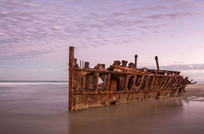 Abandoned boat on sea against sky