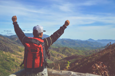 Rear view of man standing by mountains against sky