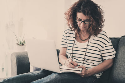 Woman writing on book at home