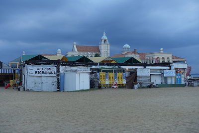 Buildings at beach against cloudy sky