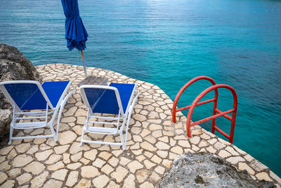 Beach chairs on a rocky cliff with a beautiful view of the caribbean sea