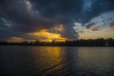 Scenic view of lake against dramatic sky during sunset