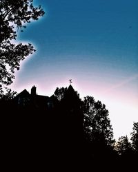 Low angle view of silhouette trees against blue sky