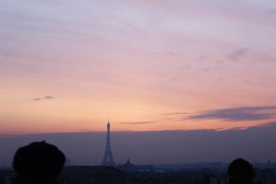 Silhouette of city against cloudy sky during sunset