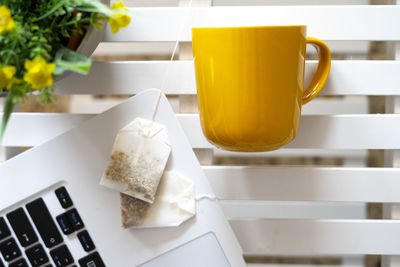 Tea bags next to a laptop and a yellow cup.