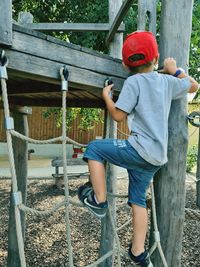 Full length of boy climbing on wooden fence