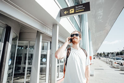 Man talking on smart phone outside airport