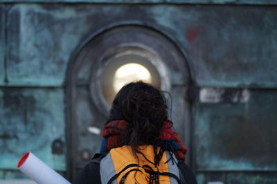Rear view of woman standing against wall