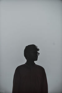 Portrait of young man looking away against sky