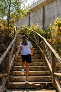 Full length rear view of woman standing on footbridge