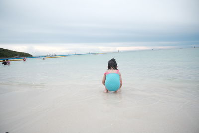 Rear view of woman on beach against sky