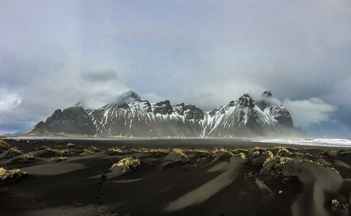 Scenic view of sea and mountain against cloudy sky