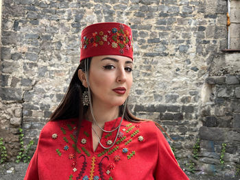 Portrait of young woman standing against wall