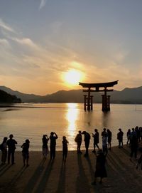 People standing at miyajima during sunset